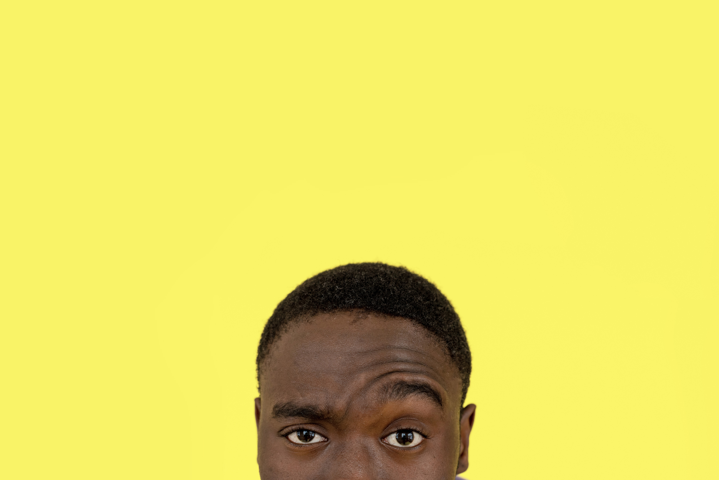 Man Raising Eye on Yellow Studio Background